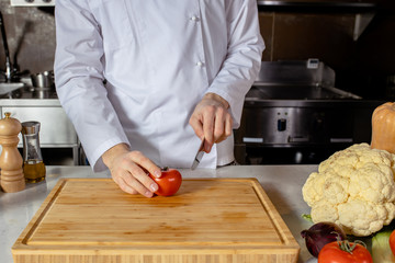 close-up photo of professional cropped cook cutting vegetables on wooden board. in kitchen. culinary concept