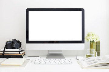 Freelance, work and creativity concept. Modern cozy workspace of photographer with peony flowers, magazine, stationary items, camera and computer with blank screen on desk. Selective focus