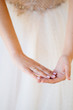 © andrey - hands of bride wedding ring on background of dress
