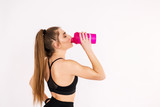 Fototapeta Łazienka - Fitness woman close-up holding a water bottle on a white background.