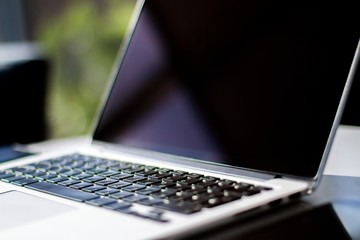 Poster - Close up of modern laptop on table in sunny interior. Business and technology concept
