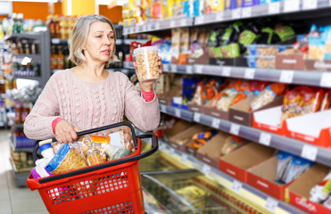 mature woman choosing food products on shelves