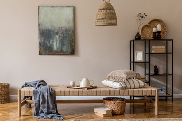 Interior design of oriental living room with modern chaise longue, pillows, plaid, rattan decoration, modern shelf, elegant personal accessories and mock up paintings on the beige wall.