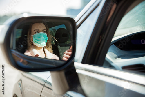 Cuadros en Lienzo Woman in protective mask driving a car on road. Safe traveling.