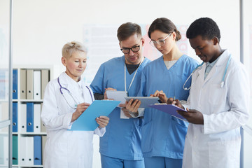 Wall Mural - Waist up portrait of medics holding clipboards while standing in medical office interior, copy space