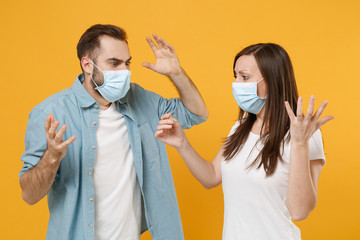 Two people in sterile face masks hold thermometer isolated on yellow background studio. Epidemic pandemic rapidly spreading coronavirus 2019-ncov medicine flu virus ill sick disease treatment concept.