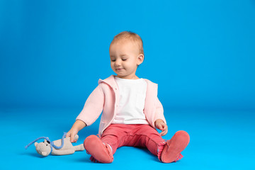 Sticker - Cute little child playing with knitted toy on light blue background