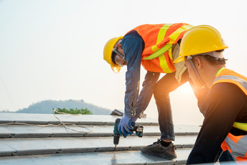 Poster - Roofer worker in protective uniform wear and gloves,Using air or pneumatic nail gun and installing concrete roof tile on top of the new roof,Concept of residential building under construction.
