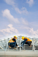 Poster - Roofer worker in protective uniform wear and gloves,Using air or pneumatic nail gun and installing concrete roof tile on top of the new roof,Concept of residential building under construction.