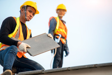 Aufkleber - Roofer worker in protective uniform wear and gloves,Using air or pneumatic nail gun and installing concrete roof tile on top of the new roof,Concept of residential building under construction.