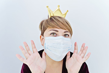 Woman wearing a crown on her head and protective face mask looking at camera