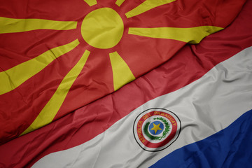 waving colorful flag of paraguay and national flag of macedonia.