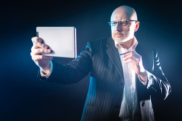 Poster - A man with an electronic tablet and a stylus in his hands. A man in a black suit draws on an electronic tablet. The person is focused on the screen of an electronic tablet.