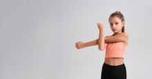 Get Fit To Be Awesome. Flexible Cute Little Girl Child Looking At Camera While Doing Exercise Isolated On A White Background. Sport, Training, Fitness, Active Lifestyle Concept. Horizontal Shot
