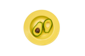 Sliced avocado in two in a yellow plate. Fresh avocado isolated on a white background. Healthy eating concept. Top view, flat lay.