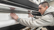 © guruXOX - Technician operator changes paper roll on large printer plotter machine