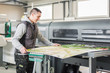 © guruXOX - Technician operator works on large premium industrial printer plotter machine