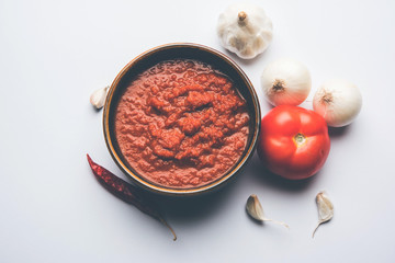 Wall Mural - onion tomato masala or puree for indian gravy, served in a bowl with raw tamatar, pays and lehsun and red chilli, selective focus