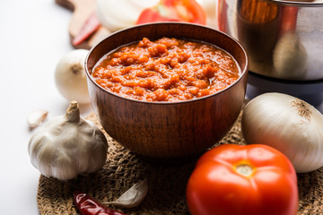 Wall Mural - onion tomato masala or puree for indian gravy, served in a bowl with raw tamatar, pays and lehsun and red chilli, selective focus