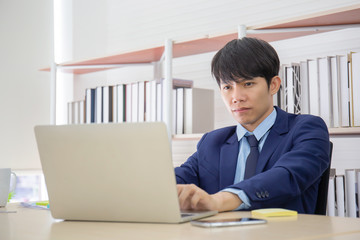 Poster - A young Asian businessman sat seriously on the desk in the office.