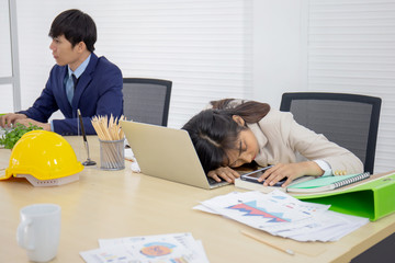 Poster - A young, professional young Asian business woman is sleeping on her desk and a male employee is working.