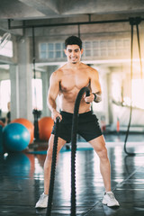 Sports man  with battle rope battle ropes exercise in the fitness gym. Fitness, gym, sport, rope, training, athlete, workout, exercises and healthy concept