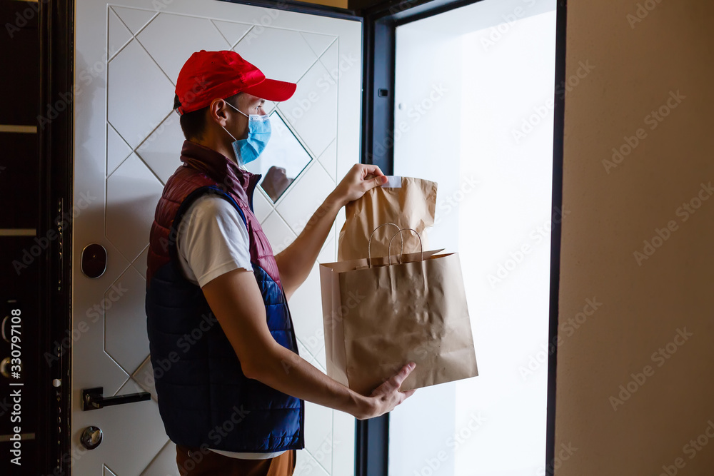 Delivery man holding paper bag with food on white background, food delivery man in protective mask - obrazy, fototapety, plakaty 