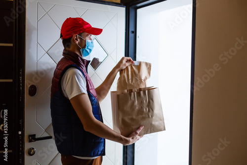 Fotomural Delivery man holding paper bag with food on white background, food delivery man