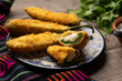 Mexican jalapeno poppers stuffed with cheese and breaded on wooden background