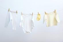 Baby Clothes On A Rope On A Colored Background. The Concept Of Washing Baby Clothes.