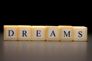 The word DREAMS written on wooden cubes, isolated on a black background...