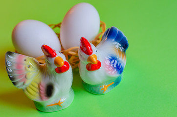 beautiful easter decoration with Figure of a rooster, hen and eggs in a basket on a green background. Copy space.