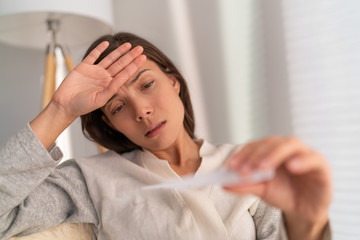 Coronavirus Asian woman checking temperature with thermometer. The corona virus causes respiratory illness (like the flu) with symptoms such as a cough, high fever and in more severe cases, pneumonia.