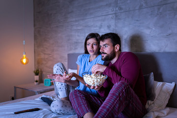 Wall Mural - Couple watching scary movie in bed