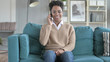 © stockbakers - The Young African Girl Talking on phone while Sitting on Couch