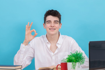 Sticker - student at the desk isolated on color background at the table with books and school supplies