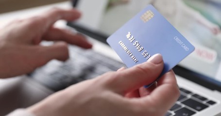 Female hands of cardholder holding credit card making e bank online payment. Woman consumer paying for purchase in web store using laptop technology. Ecommerce website payments concept. Close up view