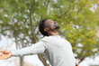 © PheelingsMedia - Black man breathing fresh air stretching arms in a park