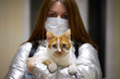 A young woman in a protective mask holds a masked cat in her arms. Conscious citizen in the fight against the epidemic of coronavirus
