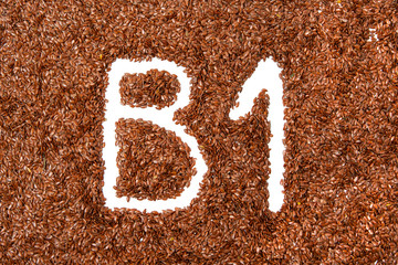 background with texture made of of brown flax seeds with a white letter of vitamin B1