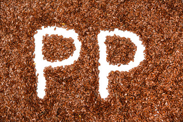 background with texture made of of brown flax seeds with a white letter of vitamin PP