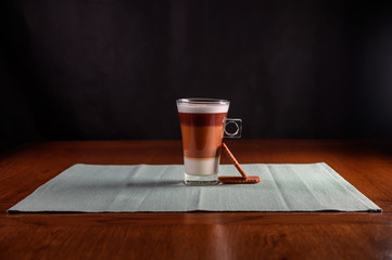 cappuccino freshly brewed into a glass cup with 2 biscuits . wooden table,