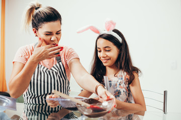 Wall Mural - Mother and daughter making homemade chocolate easter eggs. Easter in Brazil.