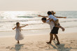 © tirachard - Asian young happy family enjoy vacation on beach in the evening. Dad, mom and kid relax playing together near sea when sunset while travel holiday. Lifestyle travel holiday vacation summer concept.