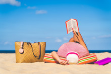 Women Are Sunbathing And Read Book On The Beach There Are Bags And Books On The Side During The Holidays In Good Weather And Clear Skies During Summer, Holidays And Activities Concept With Copy Space.