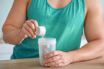 Sporty man making protein shake at home, closeup