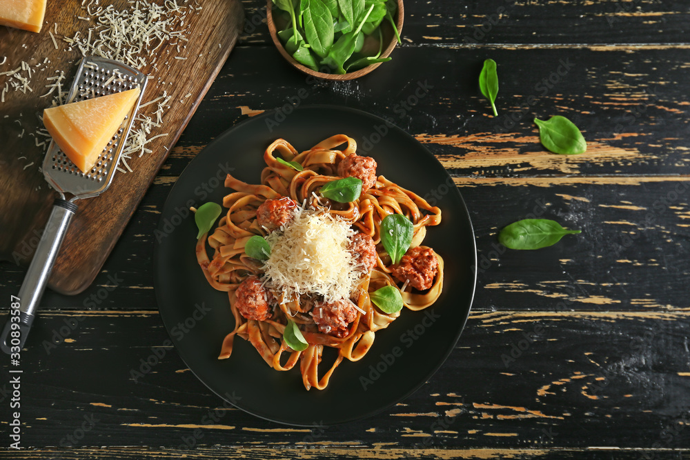 Plate with tasty pasta and cheese on dark table