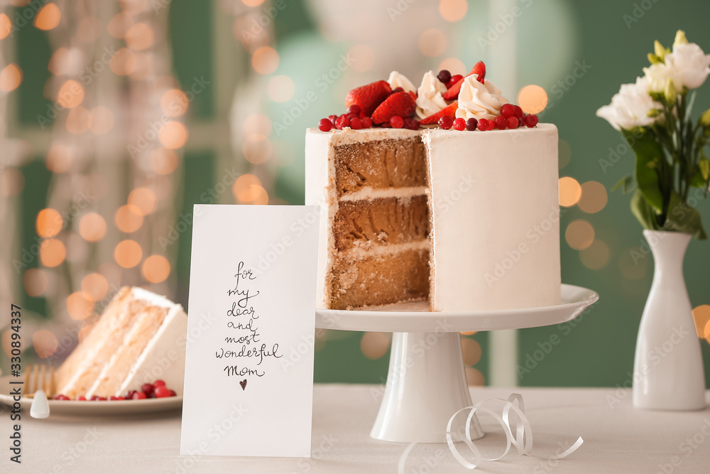 Tasty cake with greeting card for mother on table