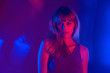 © insta_photos - Fashion attractive young blond hair 20s teenage girl model looking at camera standing at purple studio background. Pretty stylish woman in violet neon party night light concept. Portrait.