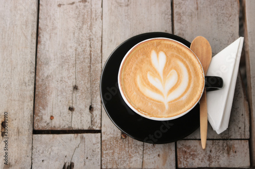 latte art coffee in black cup on wood table background Tableau sur Toile